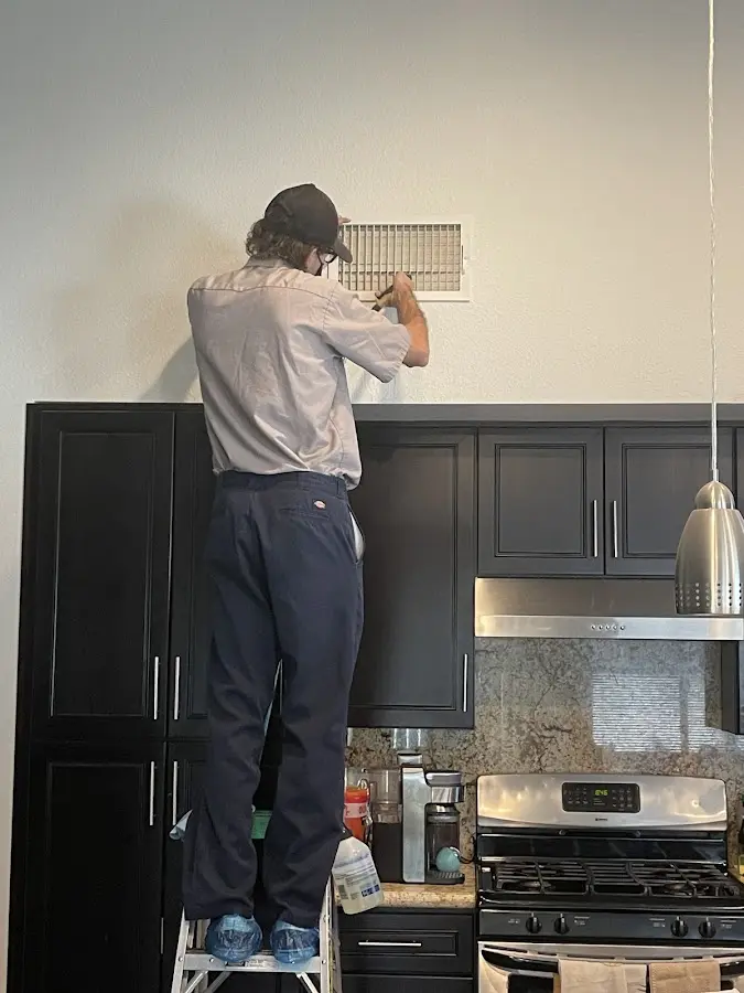 Technician inspecting an air vent during HVAC service in Acushnet